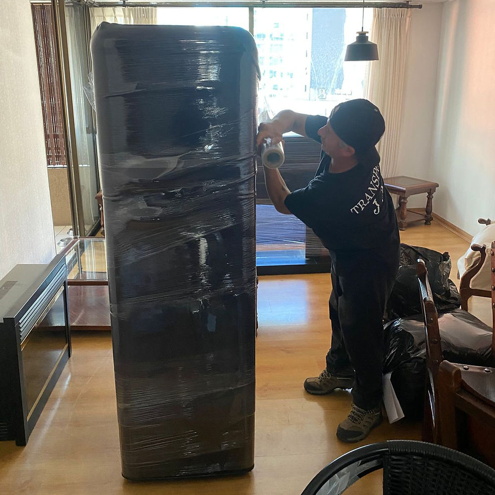 Personal de empresa de mudanzas santiago embalando un mueble