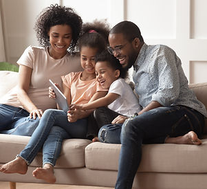 Happy african family having fun with device at home, black parents and little children usi