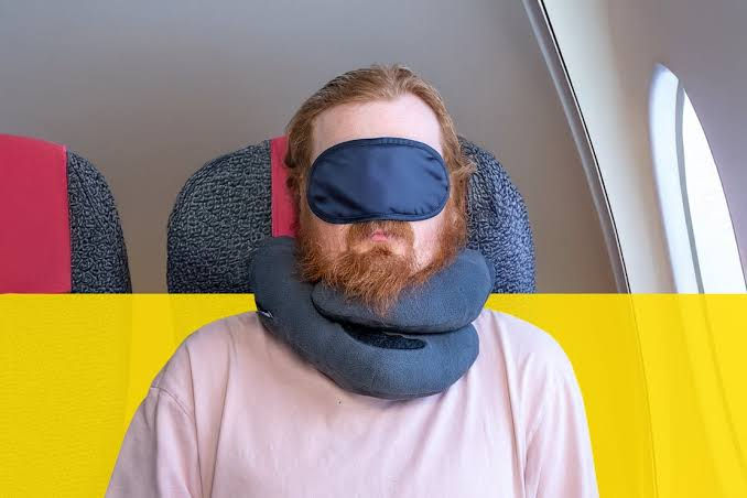 Thumbnail: Man sleeping on a plane with a comfortable travel neck pillow and eye mask.