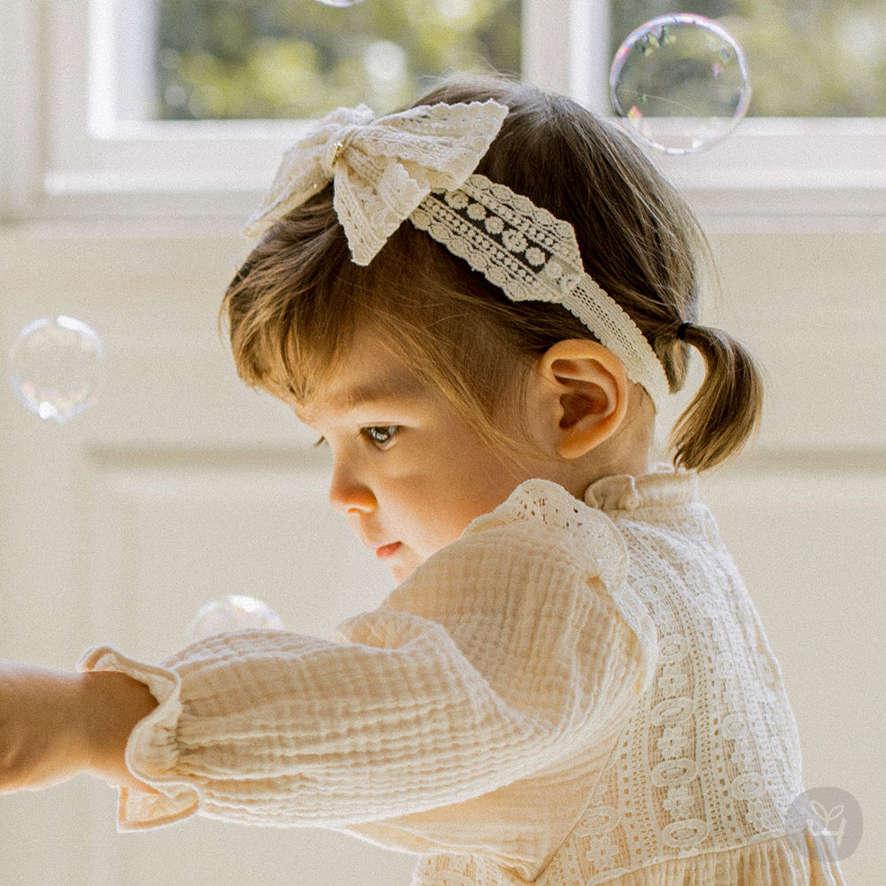 This lovely ribbed lace baby hairband features a bright lace ribbon as an accent. The luxurious lace holds the head securely.