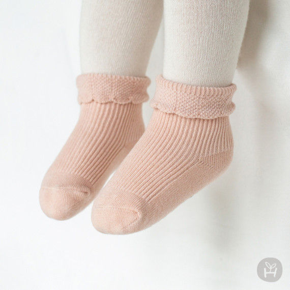 The Dain baby socks showcase a classic ribbed structure complemented by a lovely petal-like finish. These socks are adorable