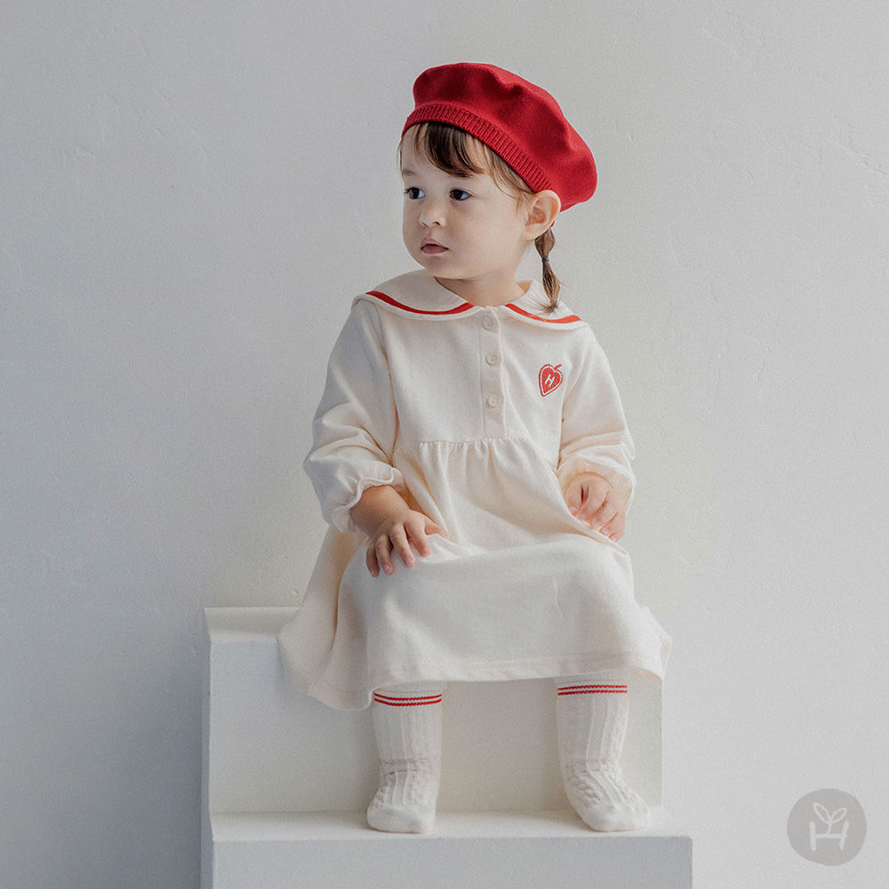 The Lopi Baby One-Piece is a lively and trendy outfit featuring a stylish red tape accent on the sailor collar. Designed with