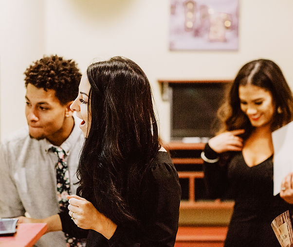 A diverse group of friends engaged in a productive meeting, brainstorming ideas and collaborating in a well-lit escape room.