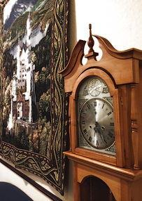 A clock on a wall beside a tapestry, adding elegance and functionality to the room's decor.