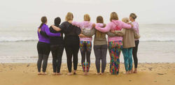 Womens Health Hub group of women with back to camera holding each other and looking out to sea