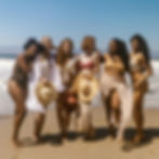 a group of women of all shapes and sizes standing together and laughing on the beach.