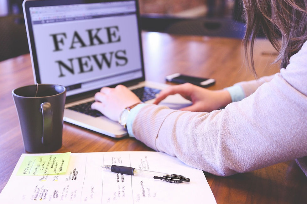 girl typing and researching on a laptop with the laptop screen reading "fake news"