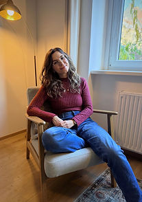 Junge Frau sitzt entspannt auf einem Sessel und lächelt sehr offen und freundlich