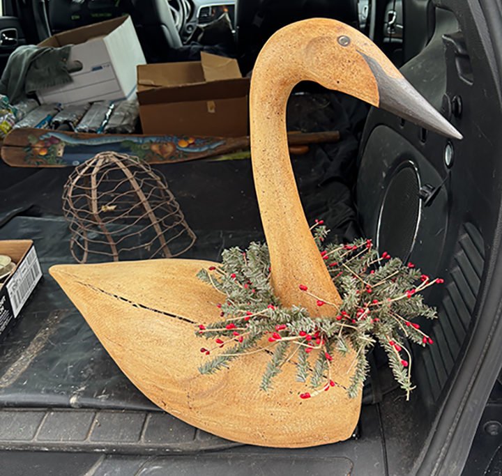 Hand carved wooden goose with a Christmas wreath around the neck.
