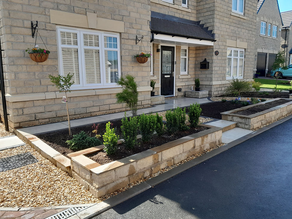 A front garden with raised beds and shrubs.