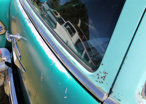 Close-up of a teal classic vehicle for sale showing chrome trim