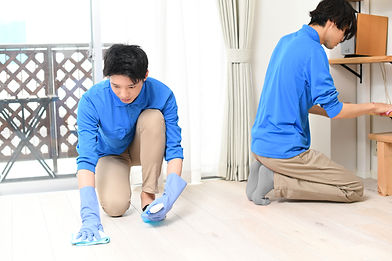 部屋で掃除をする清掃業の作業服の複数の若い男性