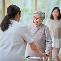 歩行する高齢女性をサポートする介護スタッフ