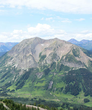 photograph of blue mountains with green trees in Colorado