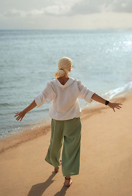 Woman standing barefoot on the beach with open arms, symbolizing clarity and emotional release during a one-on-one life coaching session with a nurse and life coach.
