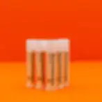 Several Apricot Lip Balm in plastic tubes in triangle formation with orange background