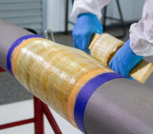 Eye-level view of a composite repair technician working on a damaged aircraft wing
