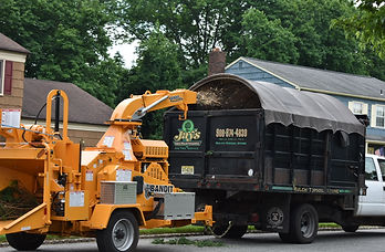 Equipment parked on the street with Jay's logos on it. They're shredding trees and you can see some bark spraying into a covered vehicle.