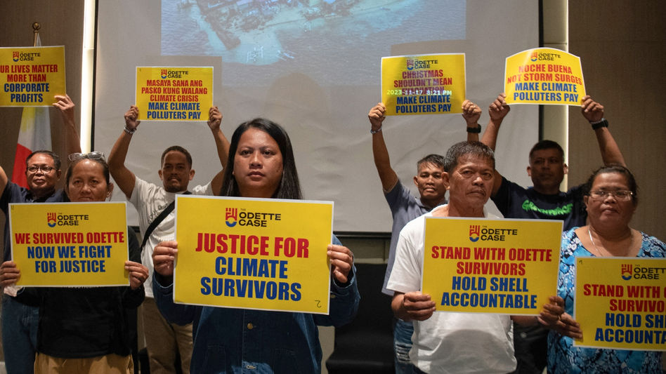 Trixy Elle, centre, holds a placard reading "Justice for Climate Survivors" alongside fellow Typhoon survivors during a Greenpeace-organized press conference.