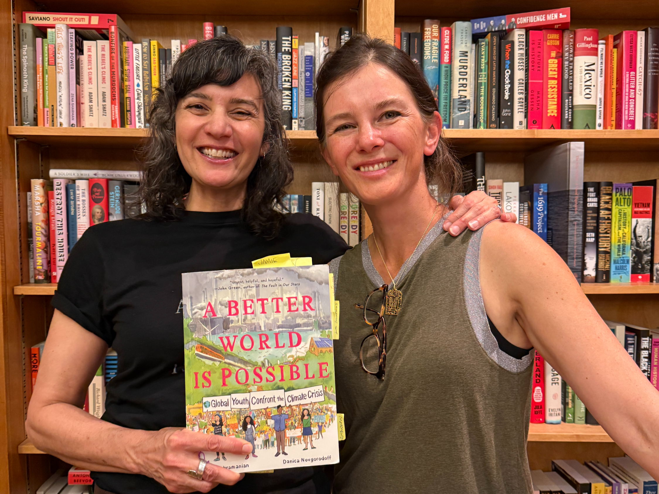 Two women pose with the graphic nonfiction book, "A Better World is Possible"