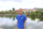 An elderly Hong Kong man in a blue polo shirt stands in front of a man-made pond.