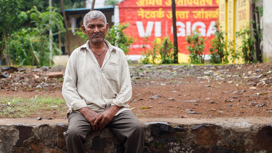 An Indian man sits in his neighborhood