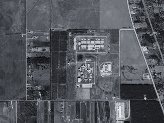 Aerial view of a large women's prison next to fields and a country road.