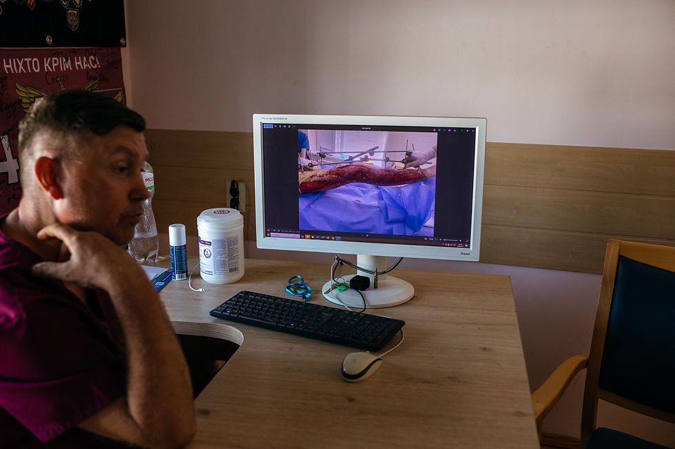 A doctor sits next to a computer screen with an imageg of a leg during surgery.