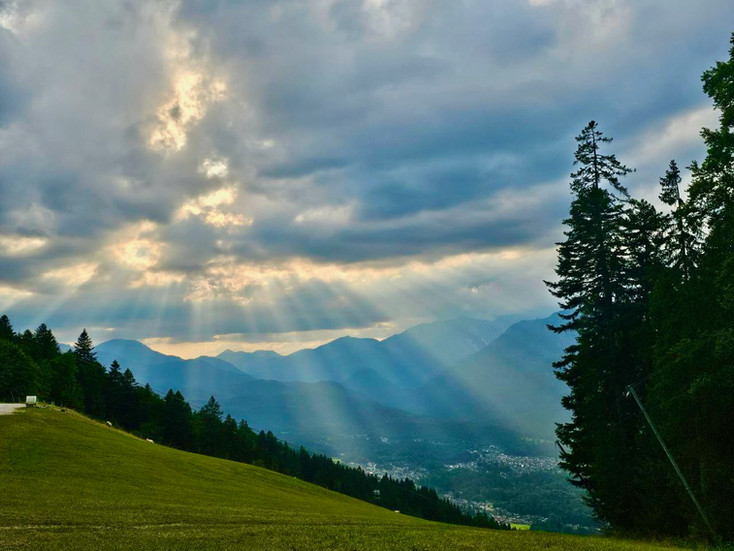 Sun rays shining through clouds over the alpine slopes of Kreuzeck