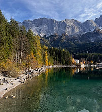 Quiet turquoise alpine lake with autumn trees and mountains beyond