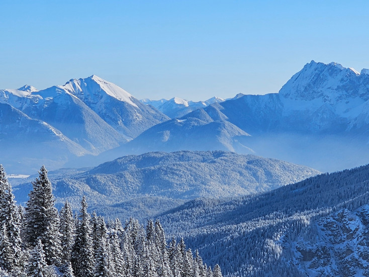 Snow-covered Alpspitze and Zugspitze peaks in winter with blue sky above