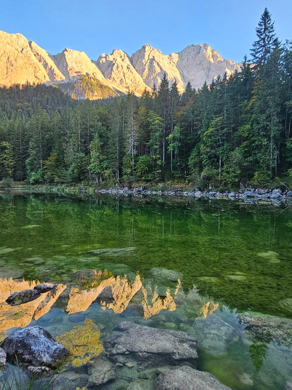 Reflection of the Zugspitze peaks in the green waters of Eibsee Lake, Bavaria.