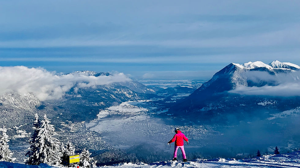 Panoramic winter view of snow-covered spruce trees and Alpine peaks at Garmisch-Classic ski resort above the clouds.