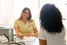 Smiling nurse consulting with a mother at a desk.