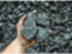 A hand holding several large rocks with raw metal in them