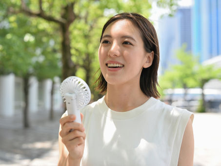 a young woman enjoying the blowing air from a handheld fan on a hot day
