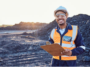 a smiling worker with a clipboard on a mining site