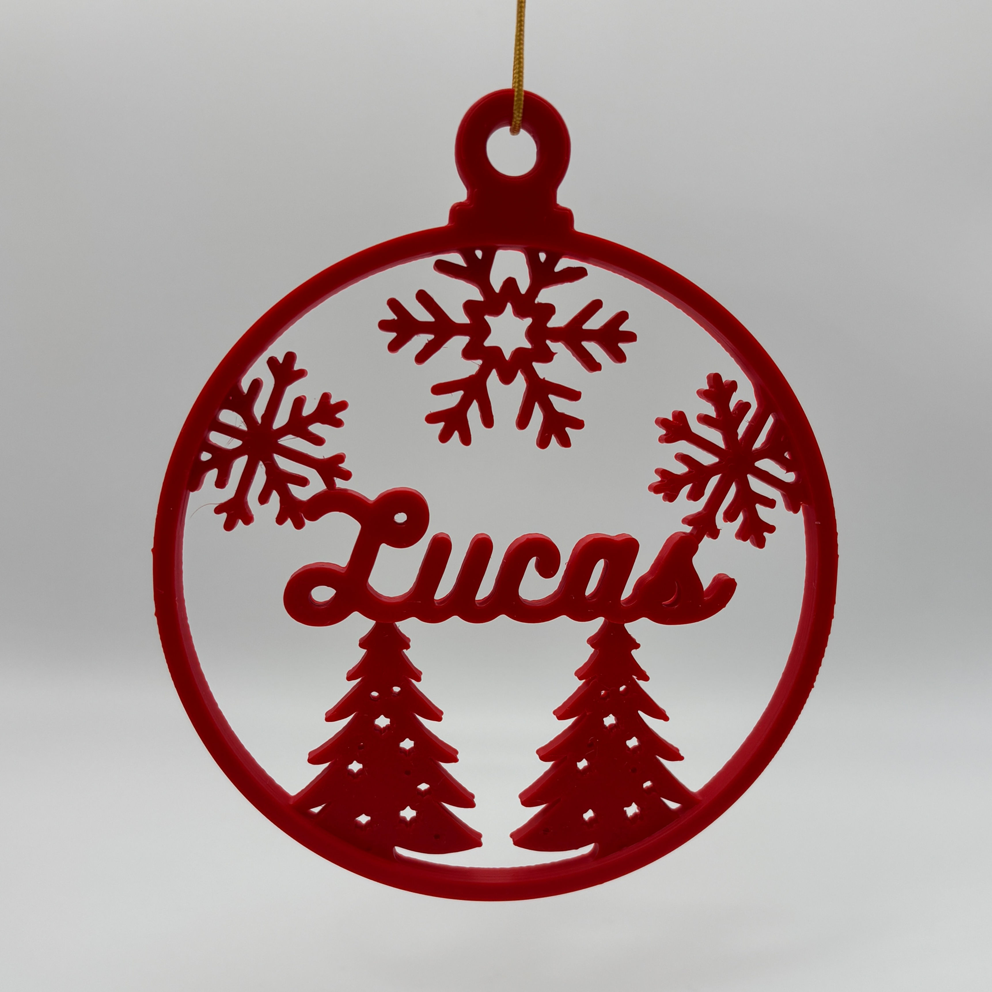 Boule de Noël rouge personnalisée avec le prénom Lucas, décor sapins et flocons