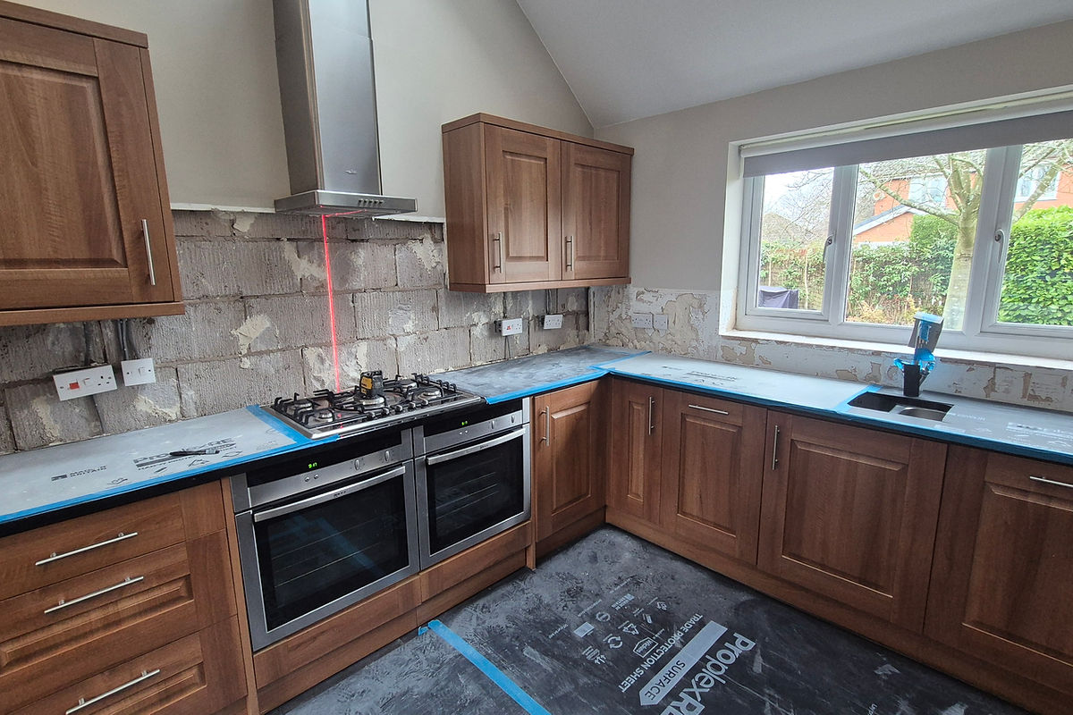 Kitchen renovation showing wooden cabinets, stainless steel appliances, and unfinished wall tiling, Warrington
