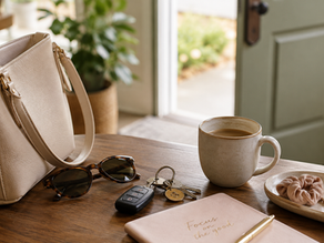 wooden desk with a leather purse, sun glasses, keys, a notebook and cup of coffee