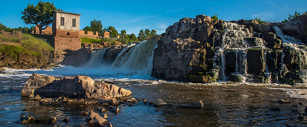 Waterfall cascading over rocky rapids with a historic building