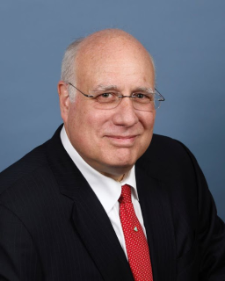 Headshot of a man in glasses and a red tie
