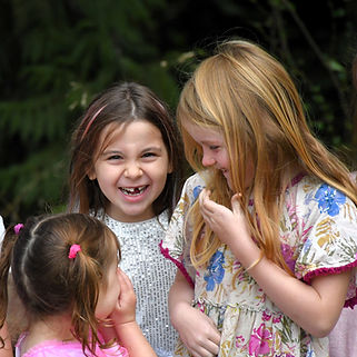 Three girls laughing together outdoors.