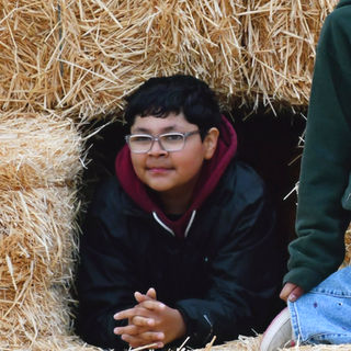 Student smiling inside a hay bale fort.