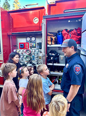 Firefighter showing equipment on a fire truck to children