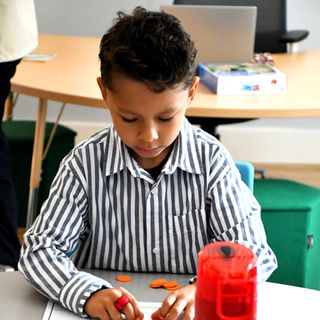 A boy in a striped shirt focused on an activity on a piece of paper.