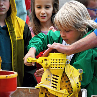 Children using a yellow apple press