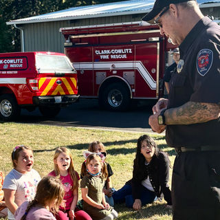 Firefighter teaching children by rescue trucks