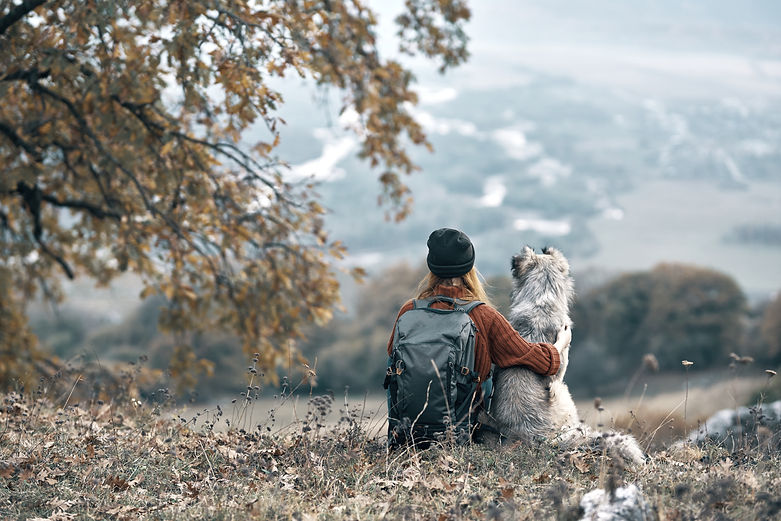 Eine Wanderin sitzt mit ihrem Hund in der Natur