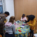 Group of diverse background girls aged 8-11 doing crafts with volunteers